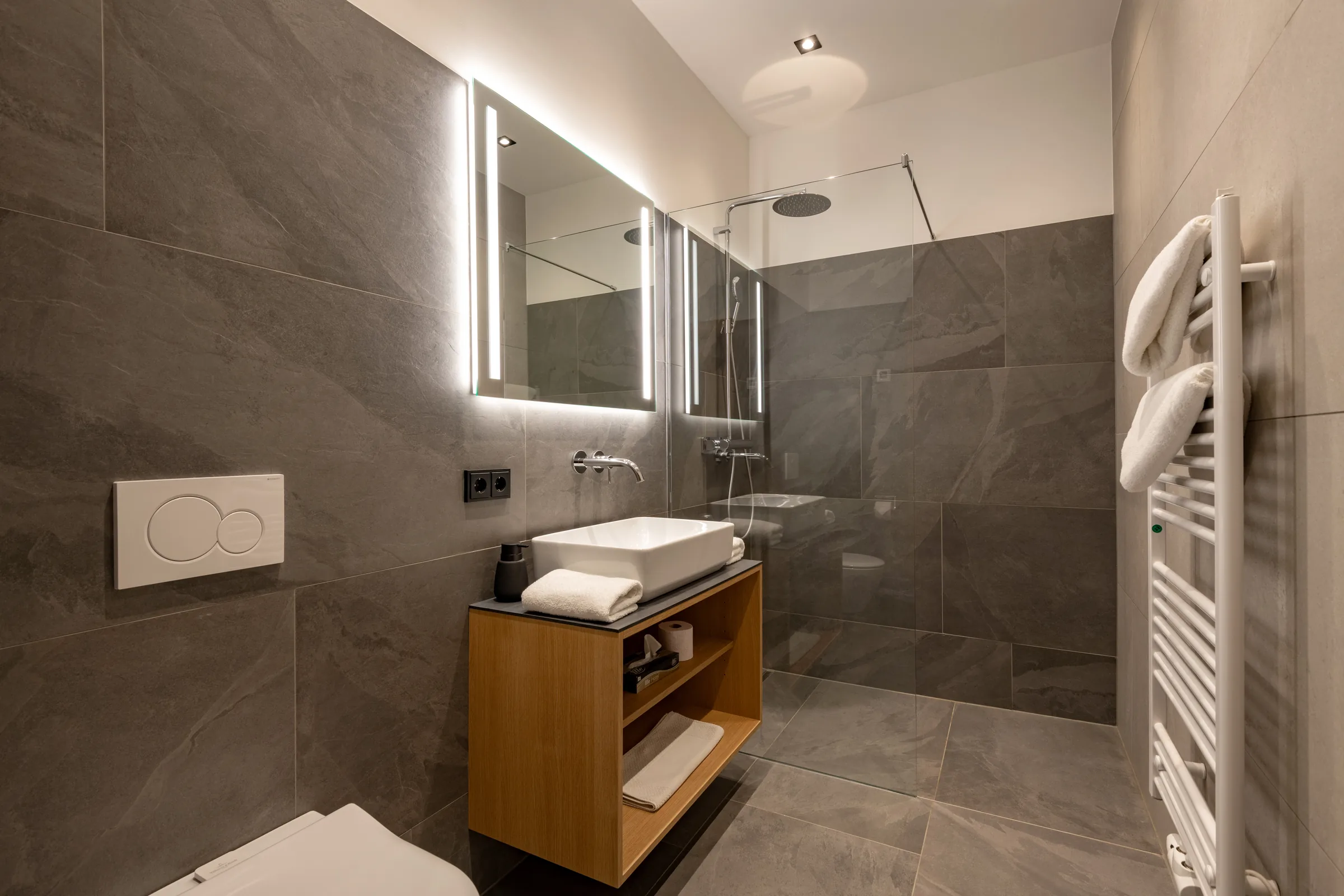 Modernes Designbad in Dunkelgrau mit bodengleicher Regendusche, LED-Spiegel und Holzwaschtisch, Studio mit Garten.